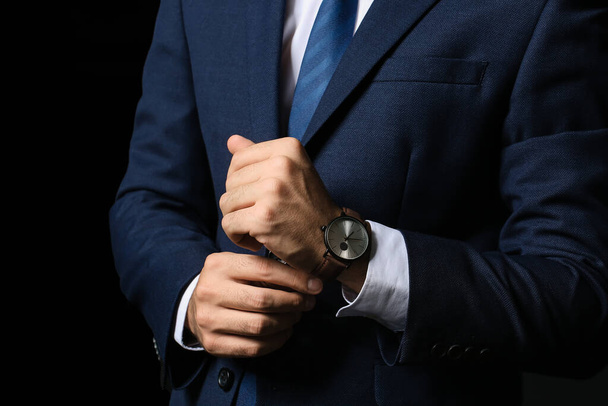 Young businessman with stylish wristwatch on dark background - Foto, Imagem