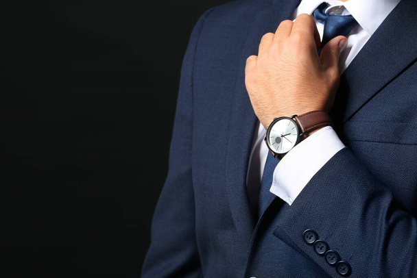 Young businessman with stylish wristwatch on dark background - Photo, Image