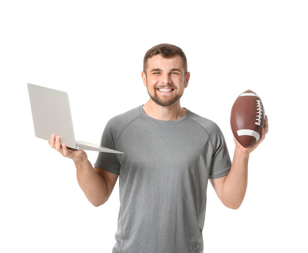 Молодой человек с ноутбуком и мячом для регби на белом фоне. Концепция спортивного пари - Фото, изображение