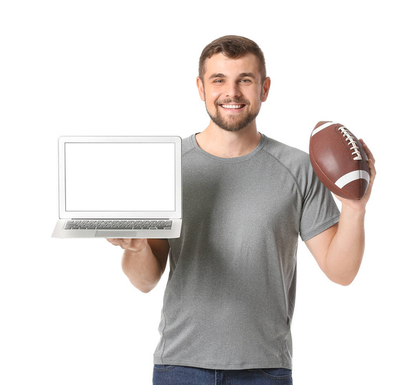 Νεαρός με φορητό υπολογιστή και μπάλα ράγκμπι σε λευκό φόντο. Έννοια του στοιχήματος αθλητισμού - Φωτογραφία, εικόνα