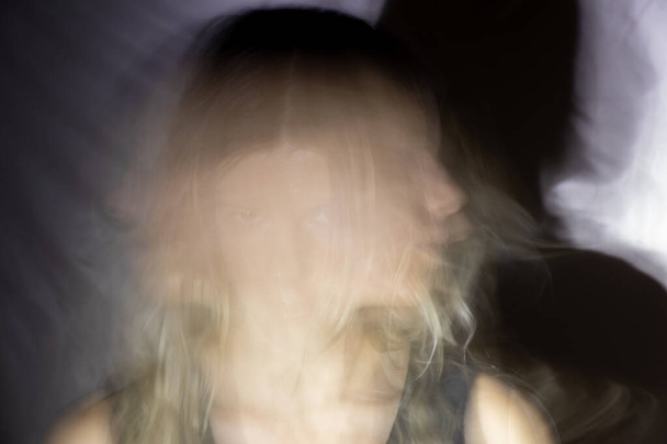 le visage d'une fille dans le noir en mouvement sur une longue exposition - Photo, image