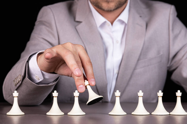 Man, businessman holds a white pawn. White pawns are in a row. - Zdjęcie, obraz