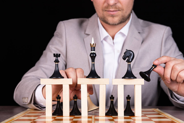ビジネスマンはチェスの駒と木製のブロックのピラミッドを作っています。建設、成長、開発、成功の概念. - 写真・画像