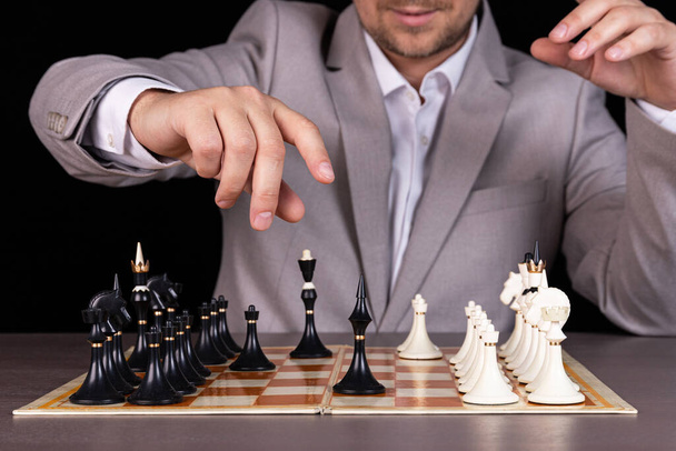 A man, a businessman plays chess, makes a move a black piece. - Zdjęcie, obraz