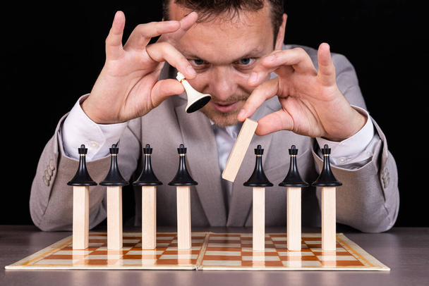 A businessman is building a pyramid of chess pieces and wooden blocks. The concept of construction, growth, development, success. - Foto, imagen