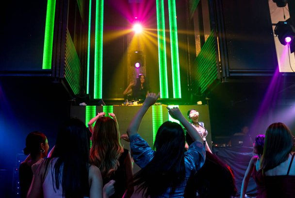 Grupo de personas bailan en discoteca al ritmo de la música de DJ en el escenario - Foto, imagen