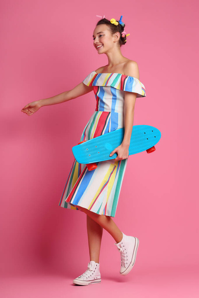 Fashion cool girl posing with a skateboard on pink background. Young hipster woman, studio shot - Foto, Bild
