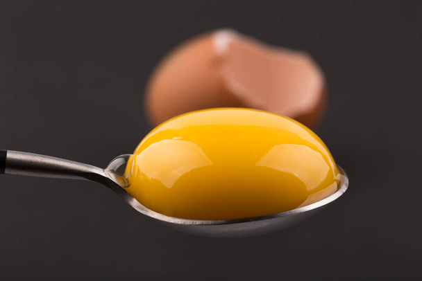 Whole and broken egg shell with egg yolk on black backgroud - Foto, Bild