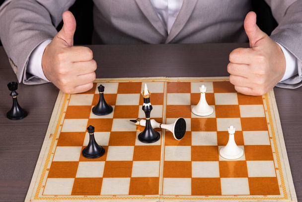 A man, a businessman plays with chess pieces, one piece beats another. The concept of power, governance, racism. - Foto, Imagen