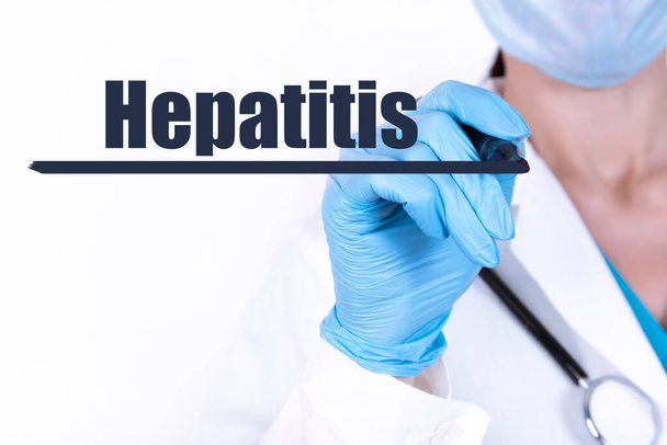 HEPATITIS text is written with a marker held by a doctor with a stethoscope. Medical concept. - Zdjęcie, obraz