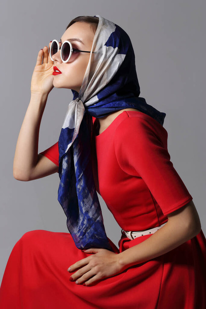 Young woman in retro style. Sunglasses and silk scarf. Sixties style fashion retro woman.  - Zdjęcie, obraz