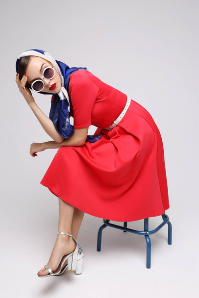 Young woman in retro style. Sunglasses and silk scarf. Sixties style fashion retro woman.  - Фото, зображення