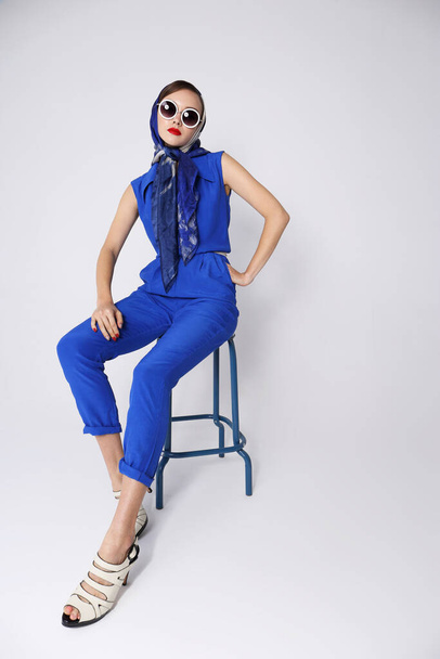 Young woman in retro style. Sunglasses and silk scarf, blue overalls. Sixties style fashion retro woman.  - Фото, зображення