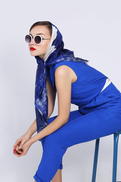 Young woman in retro style. Sunglasses and silk scarf, blue overalls. Sixties style fashion retro woman.  - Фото, изображение