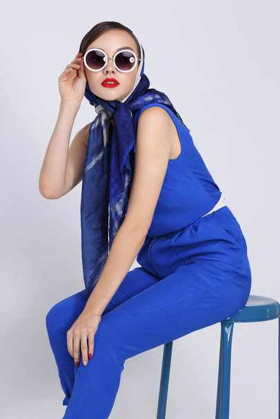 Young woman in retro style. Sunglasses and silk scarf, blue overalls. Sixties style fashion retro woman.  - Foto, Imagen