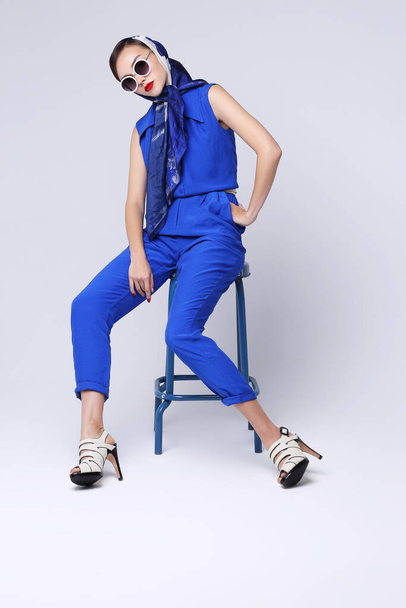 Young woman in retro style. Sunglasses and silk scarf, blue overalls. Sixties style fashion retro woman.  - Photo, image