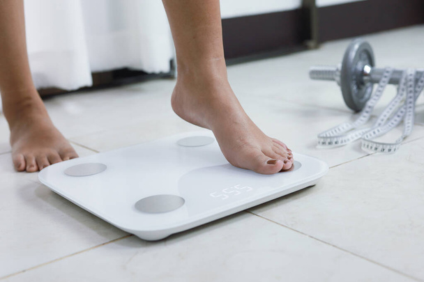 feet standing on electronic scales for weight control. Measurement instrument in kilogram for a diet control - Fotó, kép