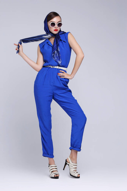 Young woman in retro style. Sunglasses and silk scarf, blue overalls. Sixties style fashion retro woman.  - Foto, Imagen