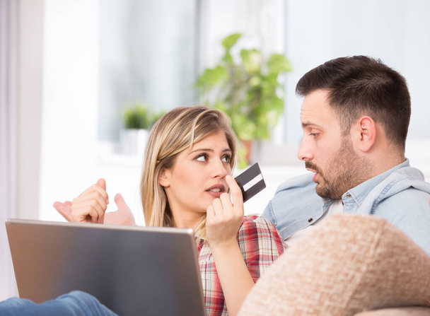 Emocionado joven pareja de compras en línea, la celebración de la tarjeta de crédito y mirando a la computadora portátil en el sofá en casa - Foto, Imagen