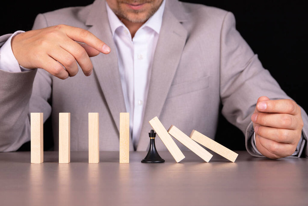 A chess pawn stops a wooden domino from falling - this is the effect of a continuous fall or risk, strategy and concept of successful intervention for a business. - Foto, Bild