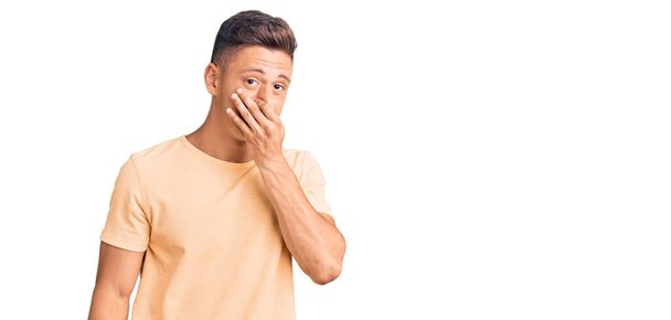 Young handsome man wearing casual clothes smelling something stinky and disgusting, intolerable smell, holding breath with fingers on nose. bad smell  - Foto, afbeelding