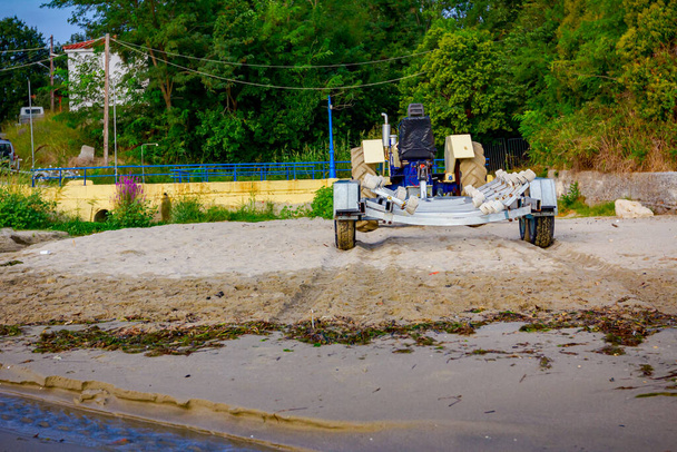 Ciągnik z pustą przyczepą jest zaparkowany na piaszczystej plaży, czeka na łodzie transportowe. - Zdjęcie, obraz