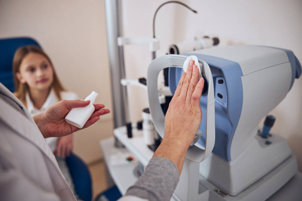 Doctor preparing special device for checking eyes in optician center - 写真・画像