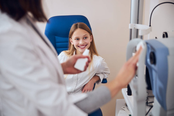 Rubia Caucásico adolescente mujer niño mirando hacia otro lado y sonriendo en el gabinete optometrista - Foto, Imagen