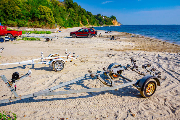 Несколько автомобилей припаркованы на пляже с прицепами для транспортных лодок. - Фото, изображение