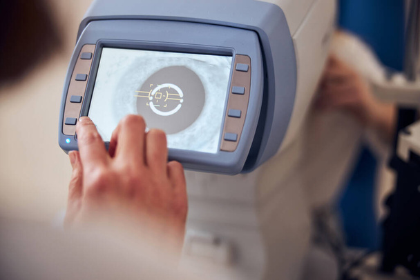Medico esperto che utilizza macchinari mentre controlla la vista del paziente in ufficio di oftalmologia pediatrica - Foto, immagini