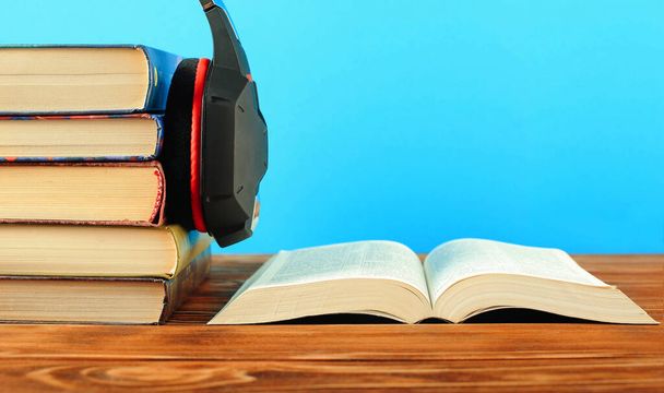 Concept for audiobooks, stacks of books and headphones on a blue background.Close-up. - Foto, Bild