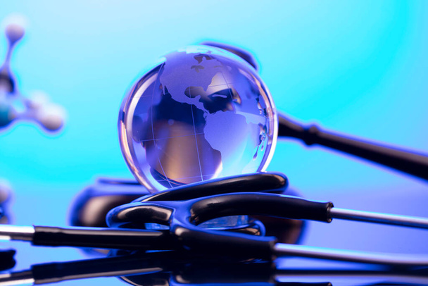 Παγκόσμια έννοια υγειονομικής περίθαλψης. Στηθοσκόπιο σε μπλε τραπέζι και φόντο. - Φωτογραφία, εικόνα