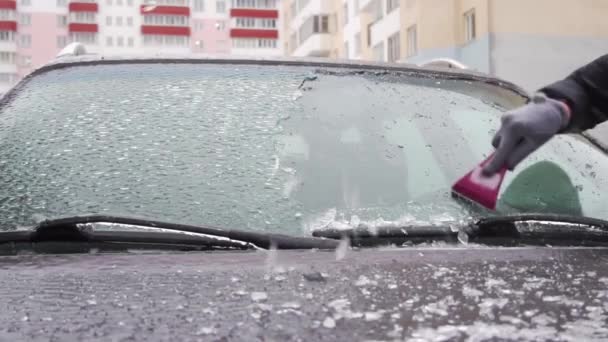 kobieta zeskrobuje lód z przedniej szyby samochodu po długim parkingu. - Materiał filmowy, wideo