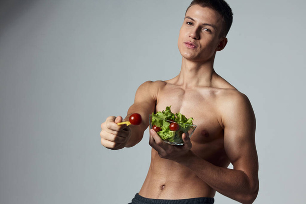 wysportowany facet z gołymi ramionami talerz sałatki zdrowe jedzenie wegetariańskie - Zdjęcie, obraz