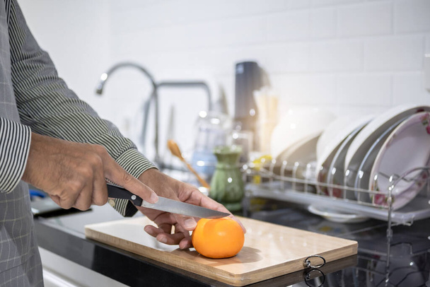 Θολή άνθρωπος ασιατικό μαγείρεμα στην κουζίνα του σπιτιού Χέρια κοπή λαχανικών και την κοπή φρούτων στην κουζίνα με μεγάλο χέρι στο φούρνο μικροκυμάτων στην κουζίνα θολή φόντο - Φωτογραφία, εικόνα