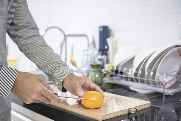 Blurred hombre asiático cocina en la cocina del hogar Él manos cortar verduras y cortar frutas en la cocina a gran mano en el microondas en la cocina fondo borroso - Foto, Imagen