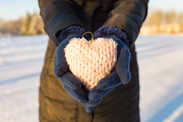 Alone Woman hands in blue gloves holding soft heart. Winter valentines day time.Closeup image. - Foto, Imagen