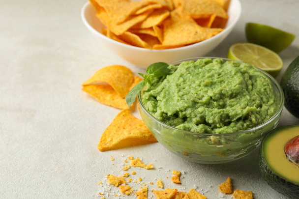 Concept of tasty eating with guacamole and chips on white textured background, space for text - 写真・画像