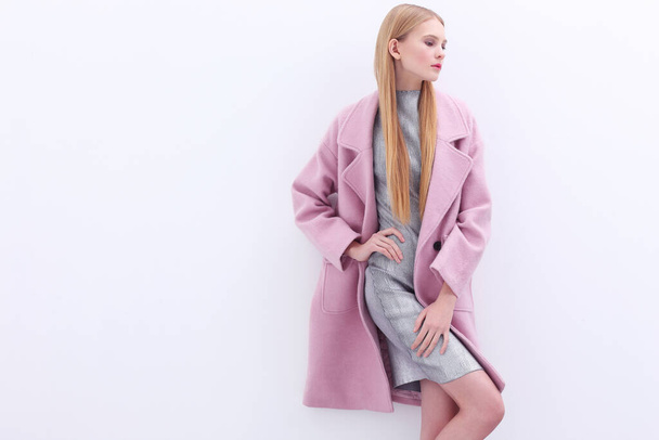 Young elegant woman in trendy pink coat. Blond hair, silver dress, isolated studio shot. - Fotografie, Obrázek