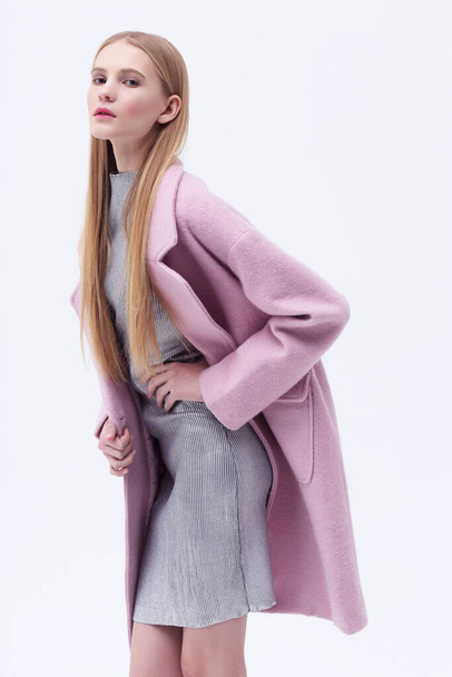 Young elegant woman in trendy pink coat. Blond hair, silver dress, isolated studio shot. - Fotó, kép