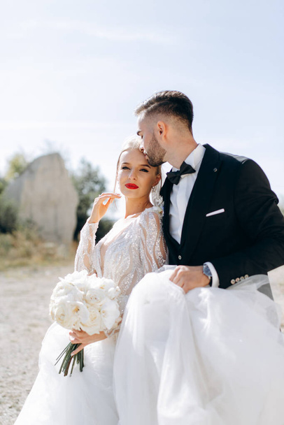 Moda y elegante retrato de cerca de hermosos recién casados en un paseo cerca de las rocas - Foto, Imagen