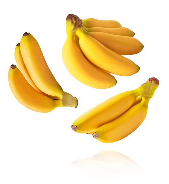 Świeżo dojrzałe banany dla dzieci spadające w powietrzu odizolowane na białym tle. Koncepcja lewitacji żywności. Obraz wysokiej rozdzielczości - Zdjęcie, obraz