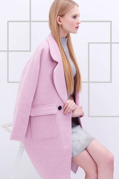 Young elegant woman in trendy pink coat. Blond hair, silver dress, isolated studio shot. - Фото, изображение