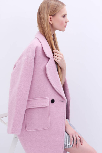 Young elegant woman in trendy pink coat. Blond hair, silver dress, isolated studio shot. - Foto, imagen