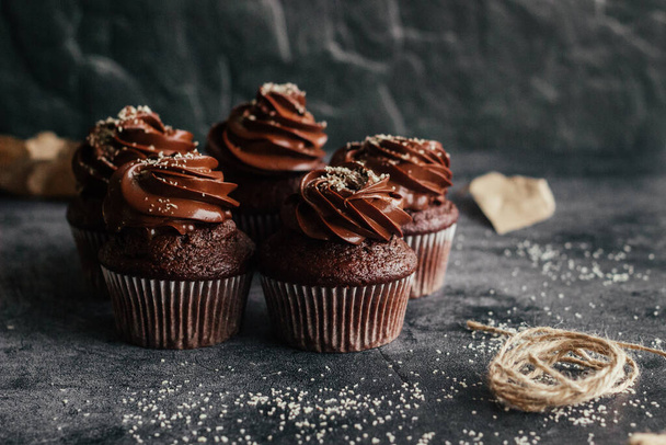 Delicious chocolate cupcakes. Cupcakes on a concrete table. Chocolate biscuit and chocolate ganache - Photo, image