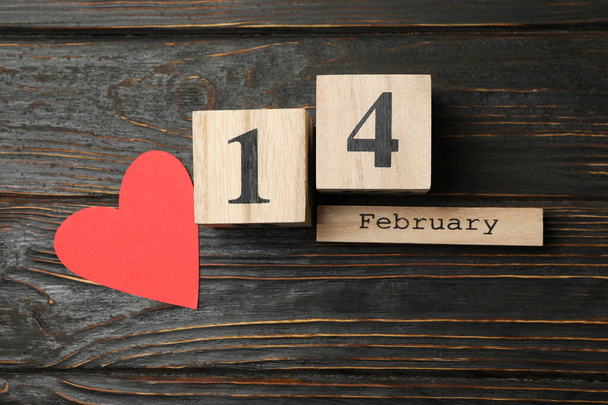 Calendario de madera con 14 febrero y corazón de papel sobre fondo de madera - Foto, imagen