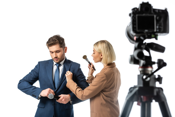 blonde makeup artist with cosmetic brush near news anchor buttoning his blazer isolated on white, blurred foreground - Foto, Imagem
