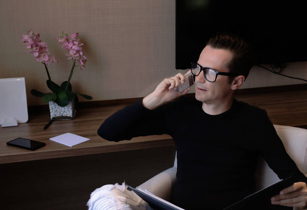 Hombre empresario va a través de informes de negocios mientras habla por teléfono en la oficina en casa. - Foto, imagen