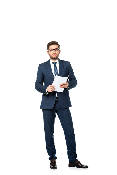 В полный рост молодой бизнесмен смотрит на камеру, держа в руках документ на белом - Фото, изображение