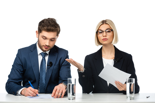 young blonde broadcaster pointing at colleague writing at workplace isolated on white - Photo, Image